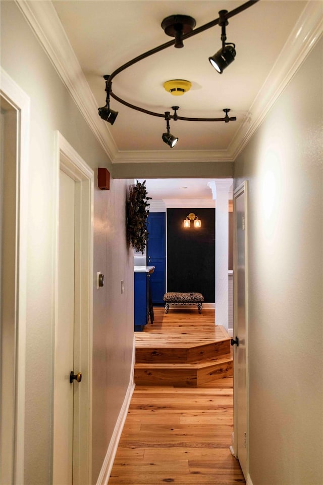 hallway featuring decorative columns, track lighting, crown molding, and light wood-type flooring