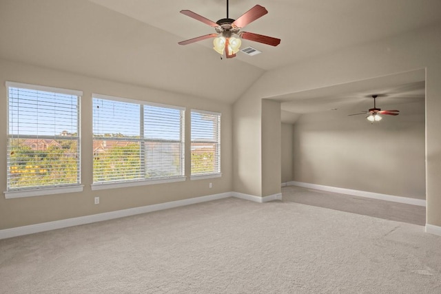 unfurnished room with vaulted ceiling, a wealth of natural light, ceiling fan, and light colored carpet