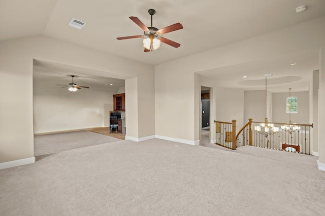 spare room with ceiling fan with notable chandelier, carpet floors, and vaulted ceiling