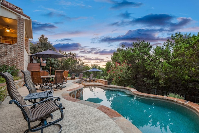 pool at dusk featuring a patio