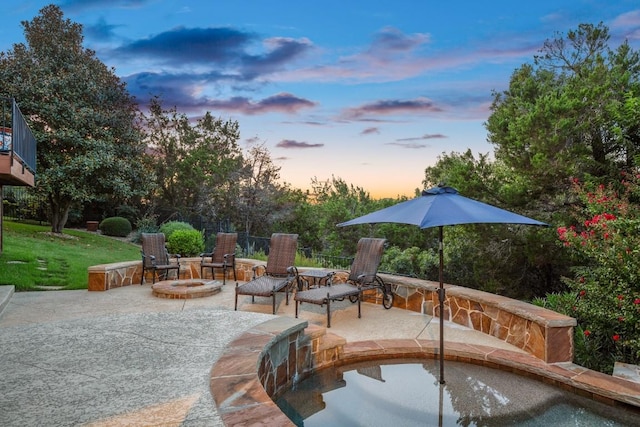 pool at dusk with a patio area and an outdoor fire pit