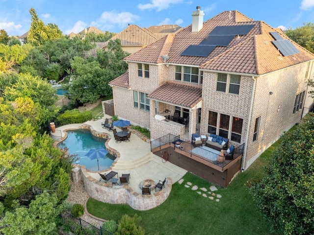 rear view of property featuring an outdoor living space with a fire pit, a chimney, outdoor dining space, solar panels, and a fenced backyard