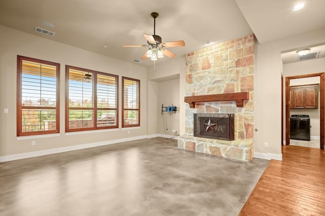 unfurnished living room featuring ceiling fan, a stone fireplace, and concrete flooring