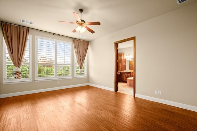 unfurnished room with light wood-type flooring, visible vents, ceiling fan, and baseboards