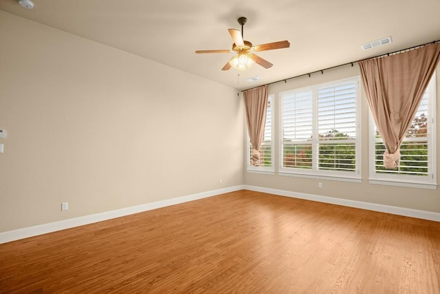 unfurnished room with baseboards, visible vents, wood finished floors, and ceiling fan