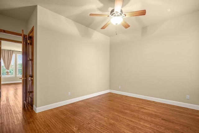 spare room featuring baseboards, wood finished floors, and a ceiling fan