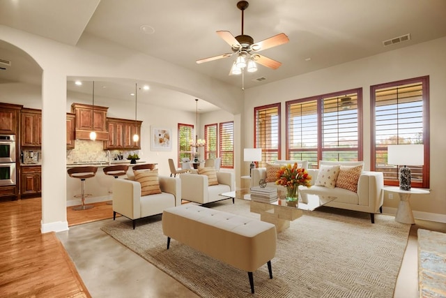 living room featuring visible vents, a ceiling fan, baseboards, and arched walkways