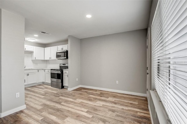 kitchen with stainless steel appliances, light hardwood / wood-style flooring, and white cabinets