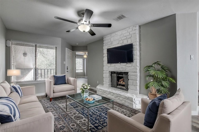 living room with a stone fireplace and ceiling fan