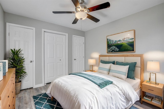 bedroom featuring ceiling fan, multiple closets, and light hardwood / wood-style floors