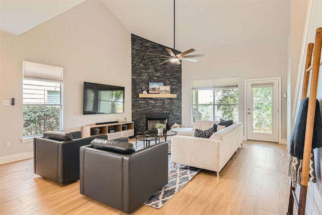 living room with ceiling fan, a fireplace, light hardwood / wood-style flooring, and high vaulted ceiling