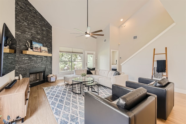 living room with high vaulted ceiling, light wood-type flooring, ceiling fan, and a fireplace