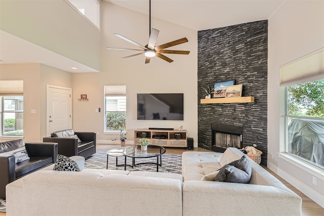 living room featuring ceiling fan, wood-type flooring, a fireplace, and high vaulted ceiling