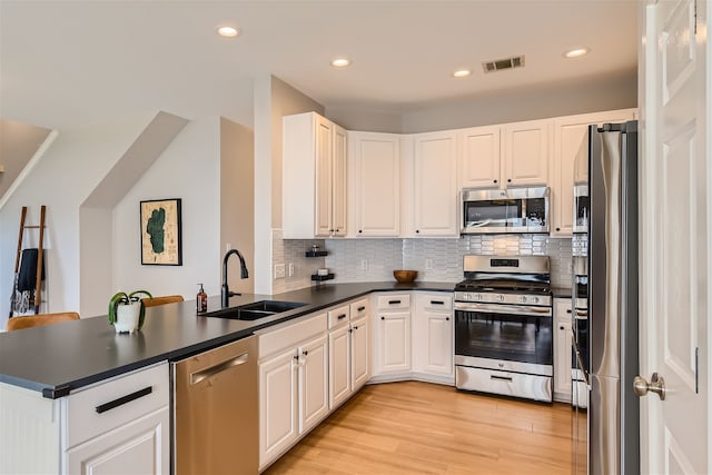 kitchen featuring kitchen peninsula, appliances with stainless steel finishes, white cabinetry, and sink