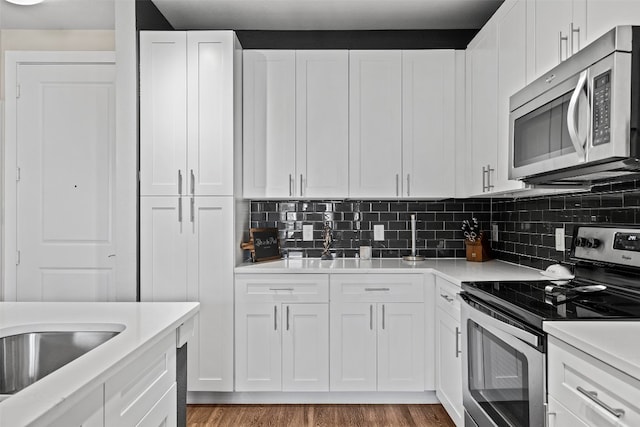 kitchen featuring white cabinets, stainless steel appliances, backsplash, and light wood-type flooring