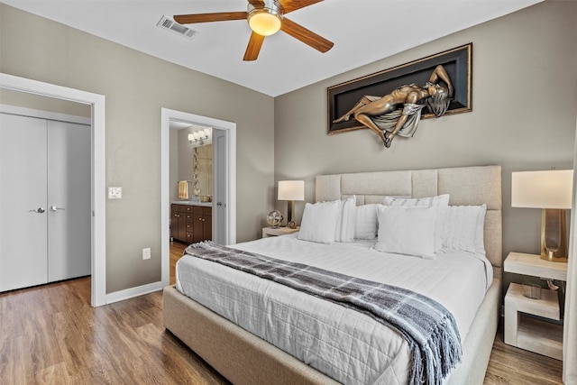 bedroom with a closet, ensuite bathroom, wood-type flooring, and ceiling fan