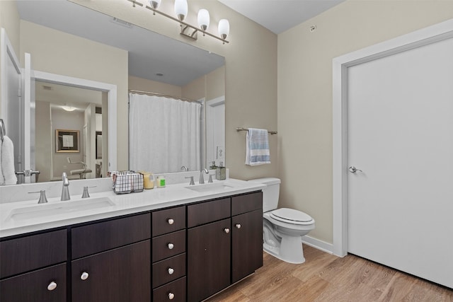 bathroom featuring dual vanity, wood-type flooring, and toilet