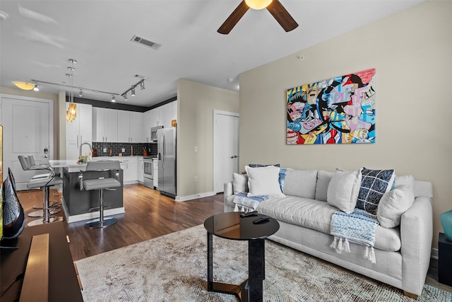 living room featuring ceiling fan, sink, dark hardwood / wood-style flooring, and track lighting