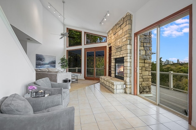 sunroom / solarium featuring a stone fireplace, vaulted ceiling, ceiling fan, and rail lighting