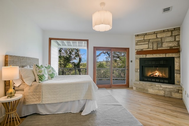 bedroom featuring a fireplace, light hardwood / wood-style floors, and access to exterior