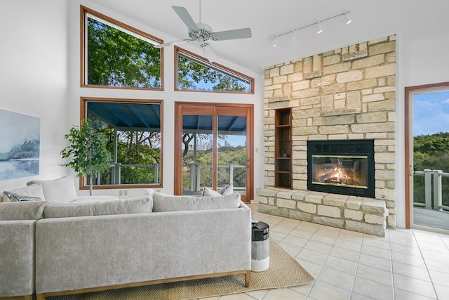 tiled living room featuring a stone fireplace, high vaulted ceiling, and ceiling fan