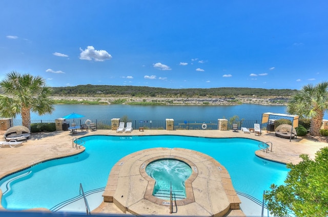 view of pool featuring a water view, a patio, and a hot tub