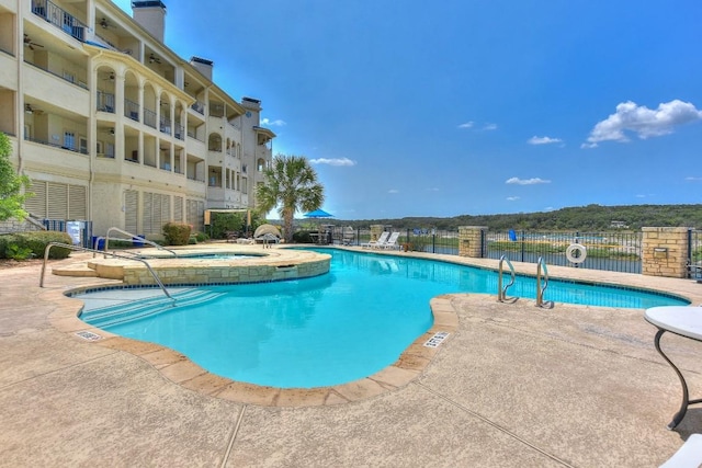 view of swimming pool featuring a patio and a hot tub