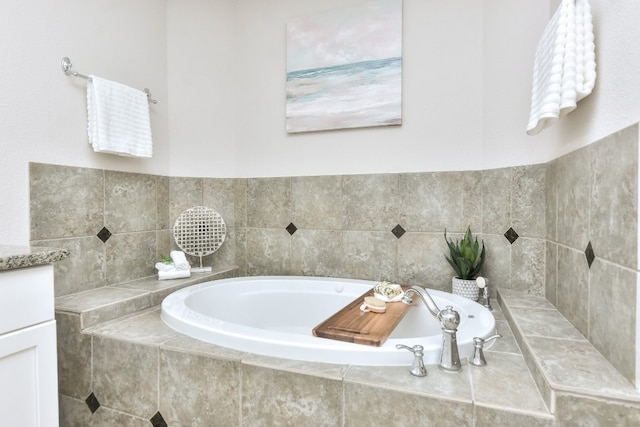 bathroom with tiled tub and vanity