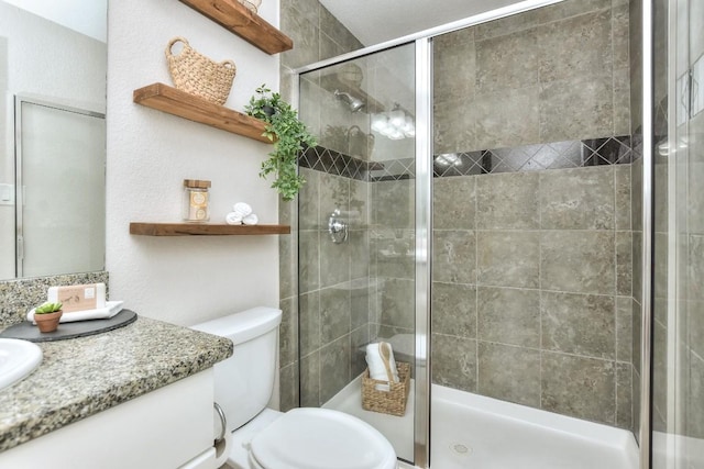 bathroom with vanity, toilet, and a shower with shower door