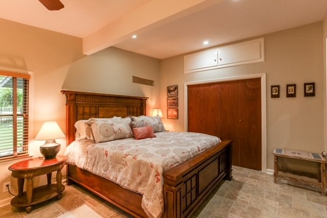 tiled bedroom featuring beamed ceiling and ceiling fan