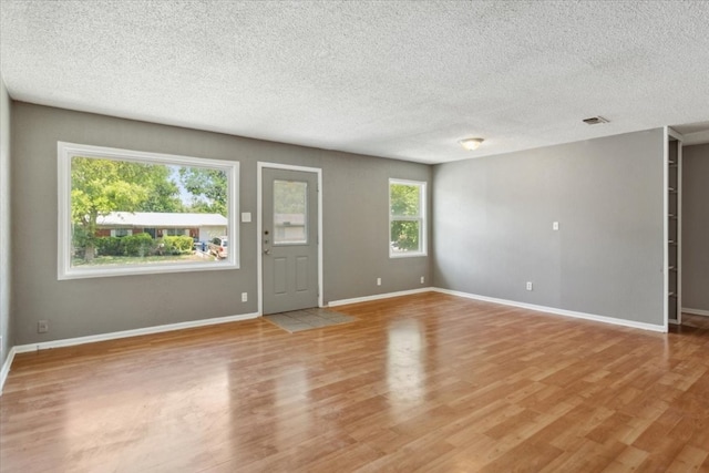 empty room with a textured ceiling and wood-type flooring