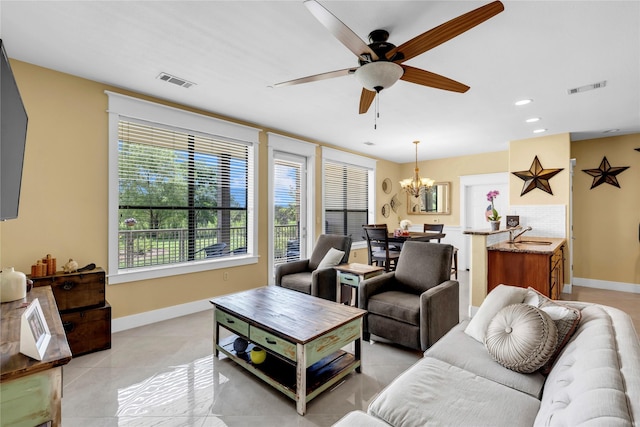 living room featuring light tile patterned floors, ceiling fan with notable chandelier, and sink