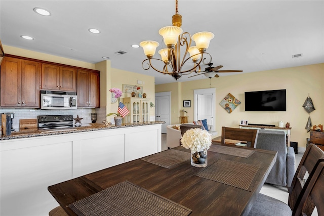 dining area featuring ceiling fan with notable chandelier