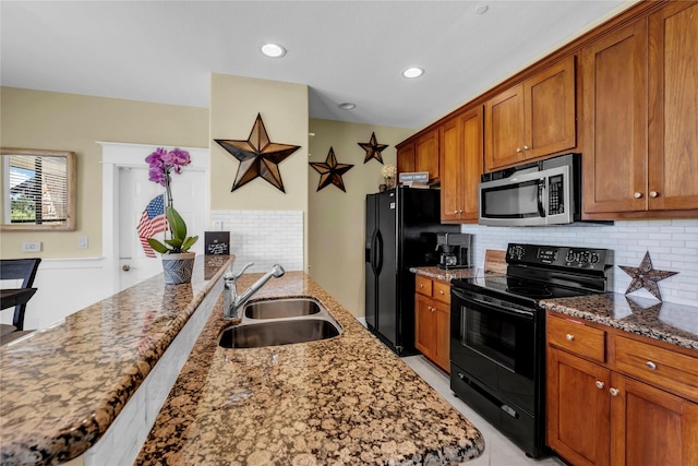 kitchen featuring sink, backsplash, light stone counters, and black appliances