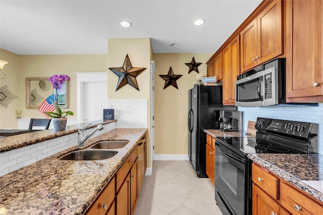 kitchen featuring sink, light tile patterned floors, tasteful backsplash, black appliances, and light stone countertops