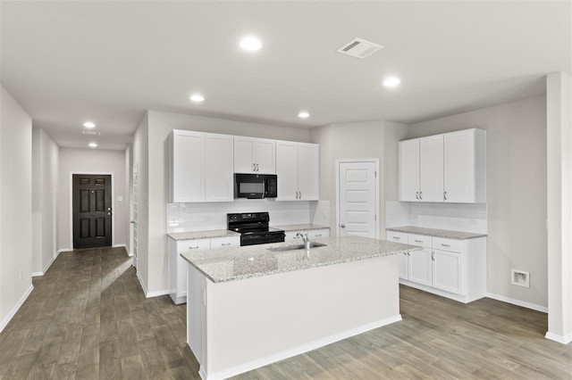 kitchen featuring white cabinetry, light stone countertops, a kitchen island with sink, and black appliances