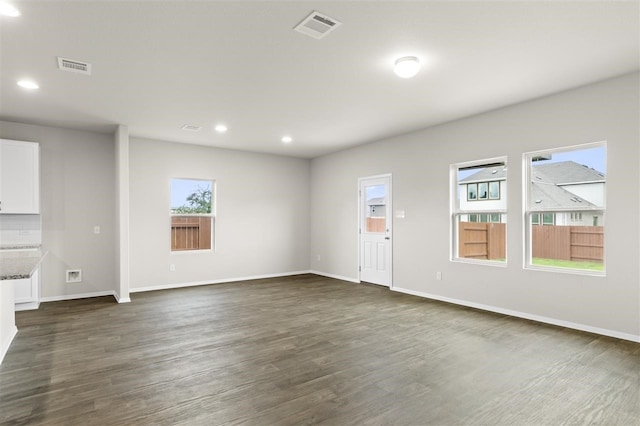 unfurnished living room featuring dark wood-type flooring and a healthy amount of sunlight