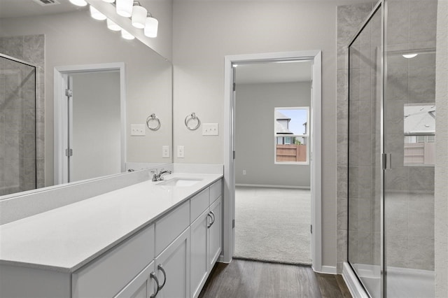 bathroom featuring hardwood / wood-style flooring, vanity, and a shower with shower door