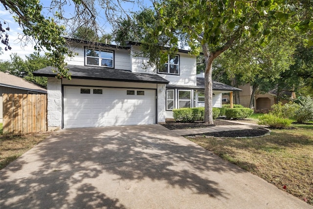 traditional-style house with a garage, fence, a front lawn, and concrete driveway