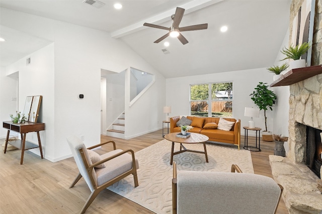 living room with high vaulted ceiling, a fireplace, beamed ceiling, light wood-type flooring, and ceiling fan