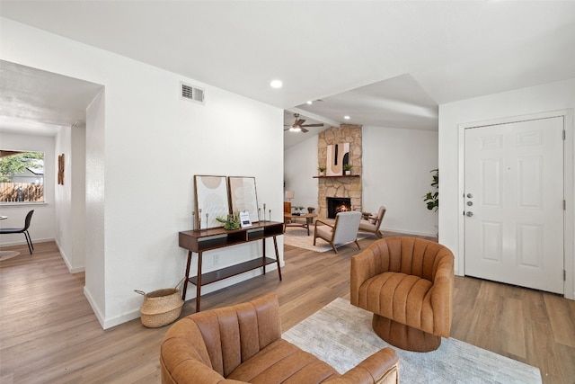 living room with ceiling fan, vaulted ceiling, light hardwood / wood-style floors, and a fireplace