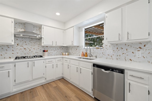 kitchen featuring white cabinets, stainless steel appliances, wall chimney exhaust hood, and sink