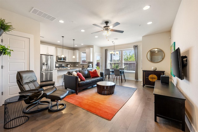 living room with dark wood-type flooring and ceiling fan with notable chandelier