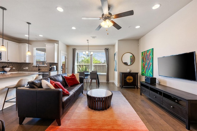 living room with ceiling fan with notable chandelier, sink, and hardwood / wood-style floors