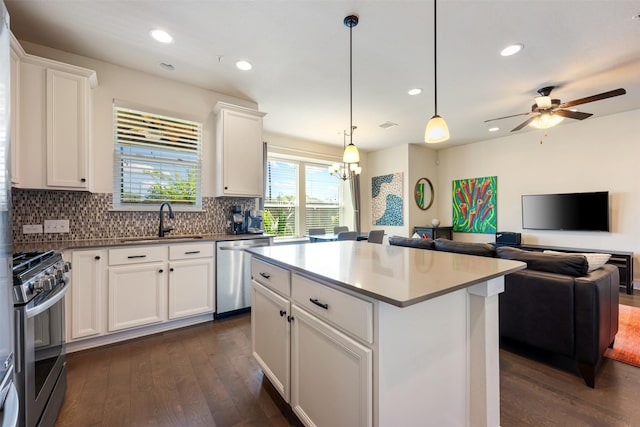 kitchen with a kitchen island, appliances with stainless steel finishes, pendant lighting, sink, and white cabinets