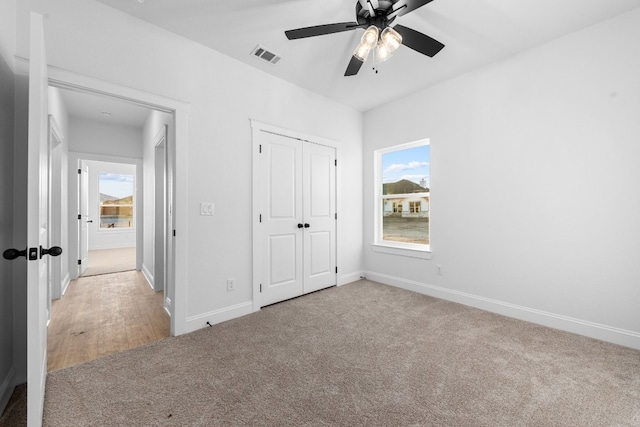 unfurnished bedroom featuring a closet, light colored carpet, and ceiling fan