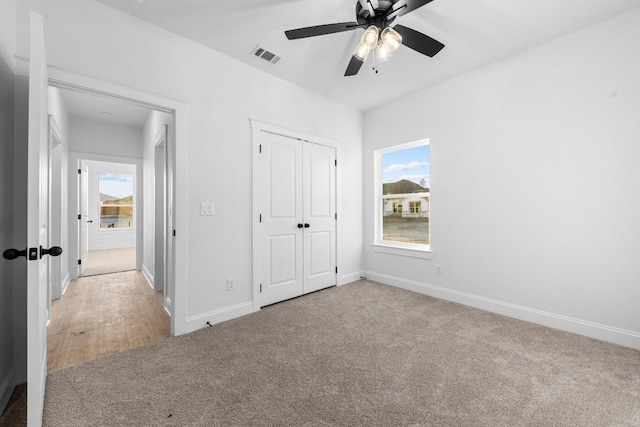 unfurnished bedroom featuring ceiling fan, a closet, and light carpet