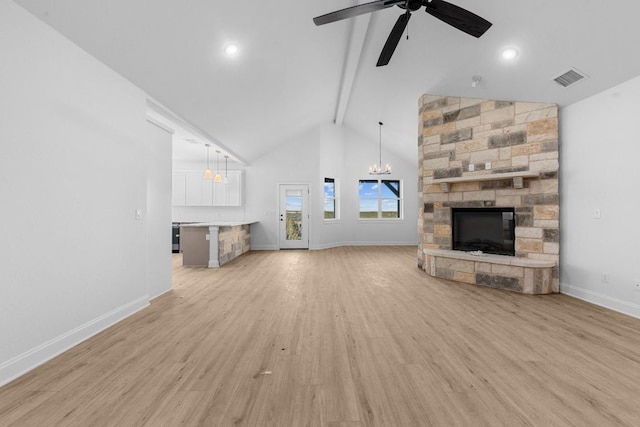 unfurnished living room with ceiling fan with notable chandelier, high vaulted ceiling, a fireplace, beam ceiling, and light hardwood / wood-style flooring