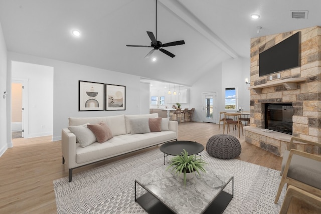 living room with a fireplace, light hardwood / wood-style floors, beam ceiling, high vaulted ceiling, and ceiling fan