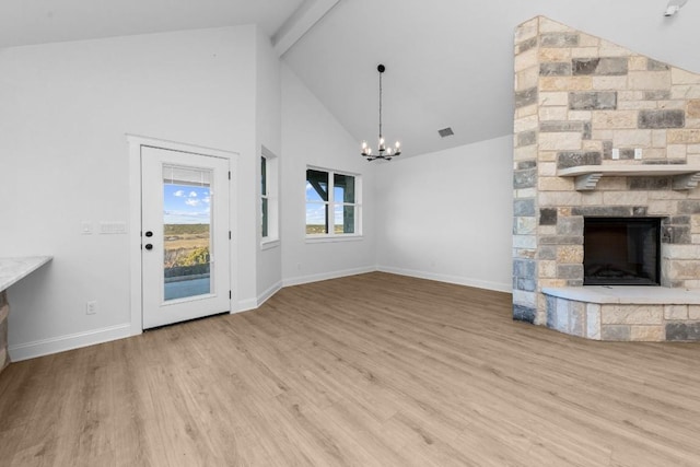 unfurnished living room featuring light hardwood / wood-style flooring, an inviting chandelier, high vaulted ceiling, a stone fireplace, and beamed ceiling